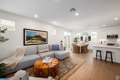 A living room with a grey couch, a coffee table, and a painting on the wall.