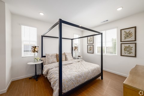 A bedroom with a four poster bed and a nightstand with a lamp.