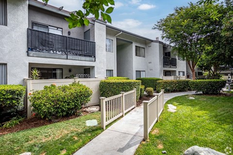 A residential building with a well-maintained lawn and a white picket fence.
