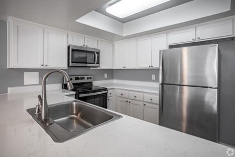 A kitchen with a stainless steel refrigerator, sink, and stove.