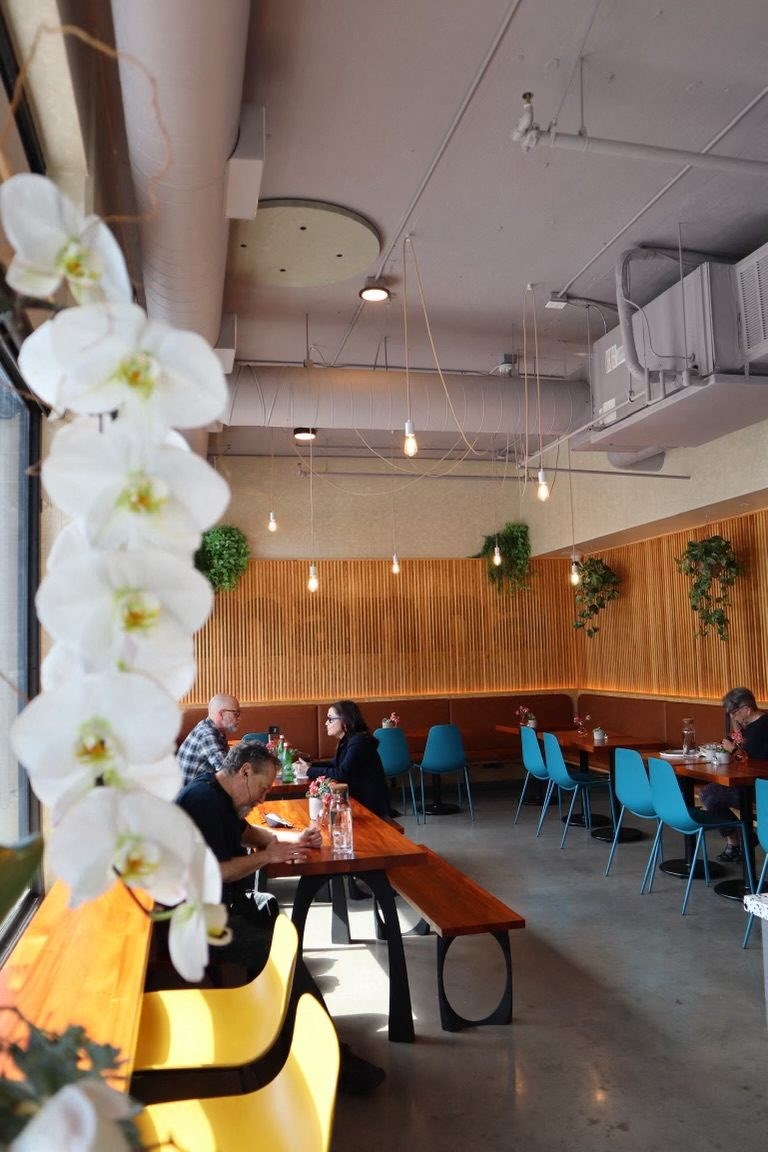 a restaurant with white flowers in the foreground and people sitting at tables in the background