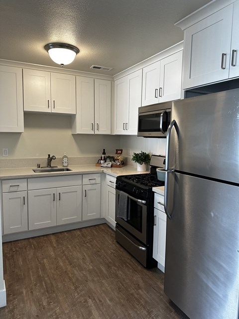 an empty kitchen with stainless steel appliances and white cabinets