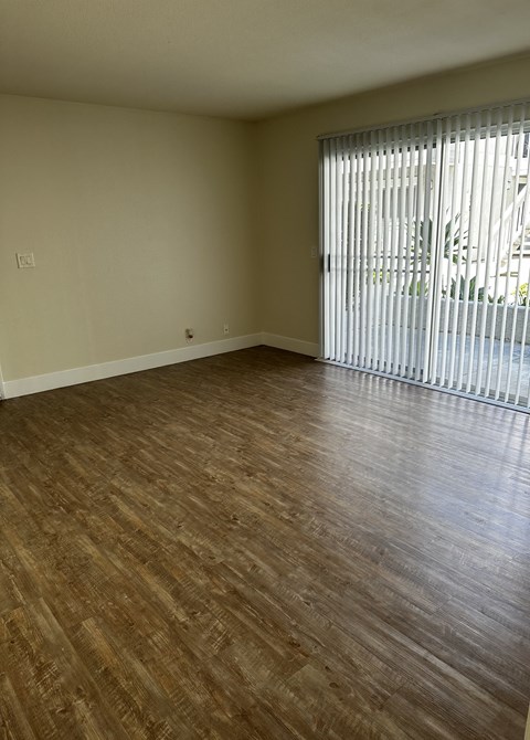 an empty living room with wood flooring and a window
