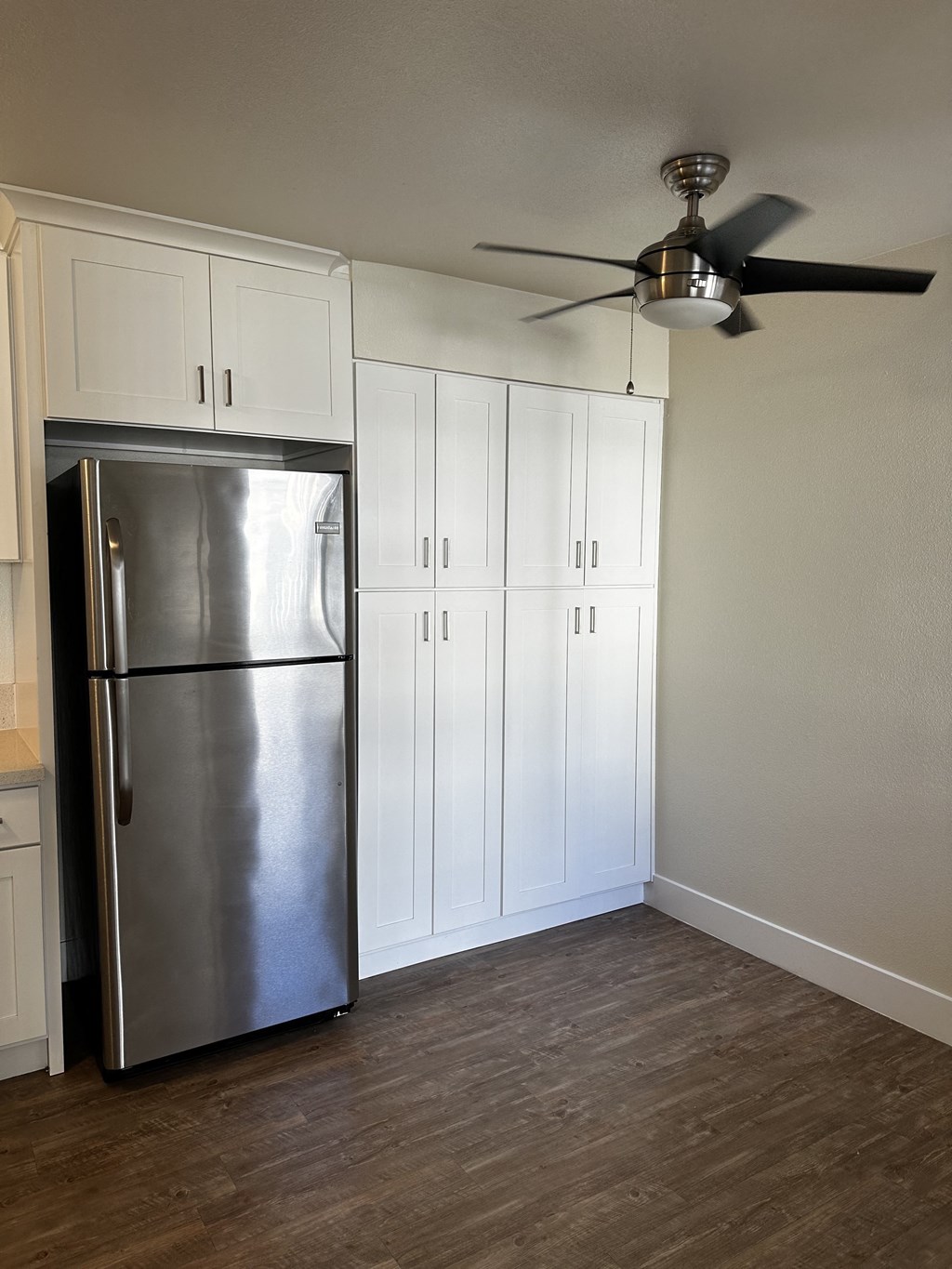 a kitchen with white cabinets and a stainless steel refrigerator