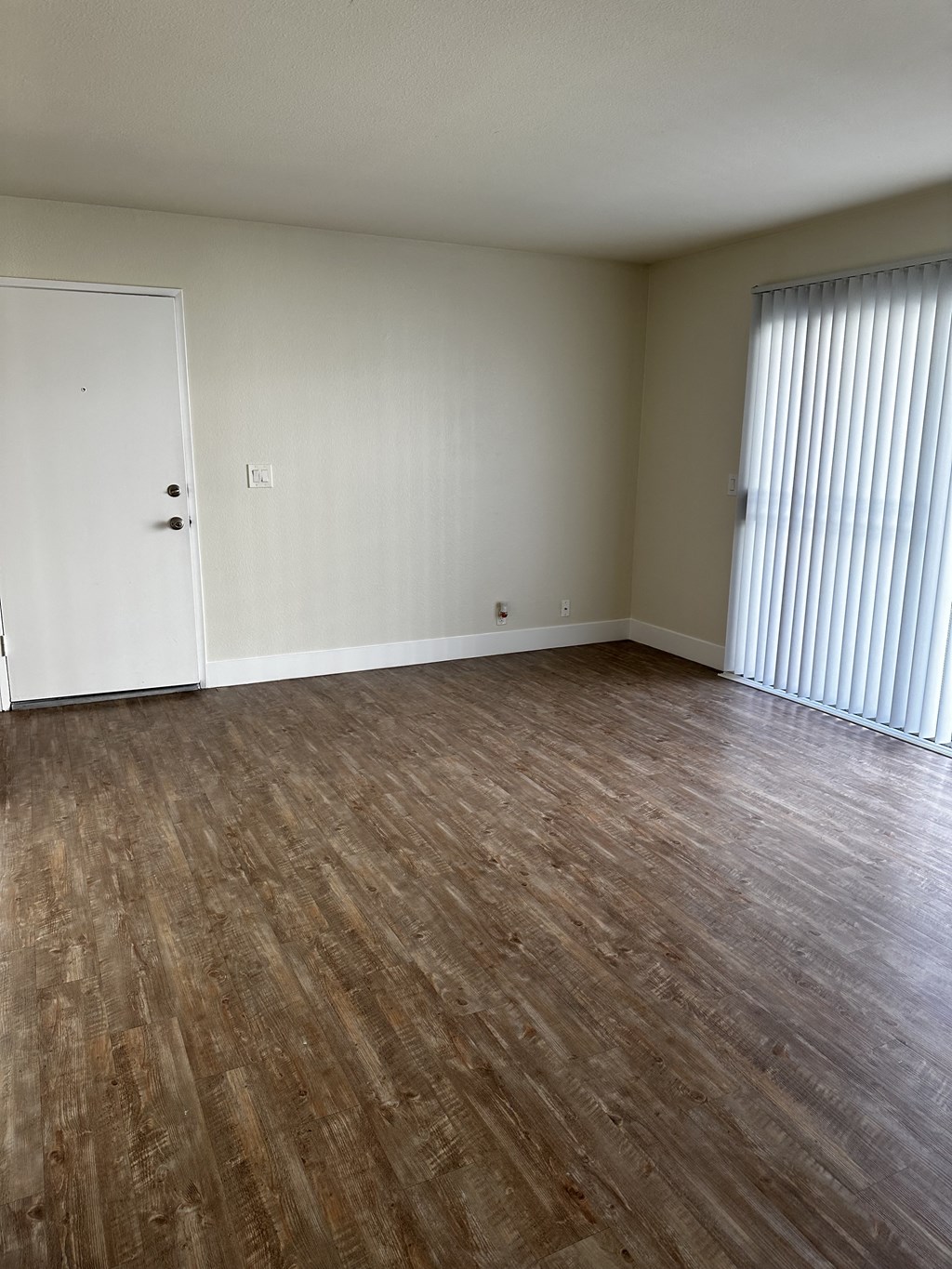 an empty living room with wood flooring and a closet