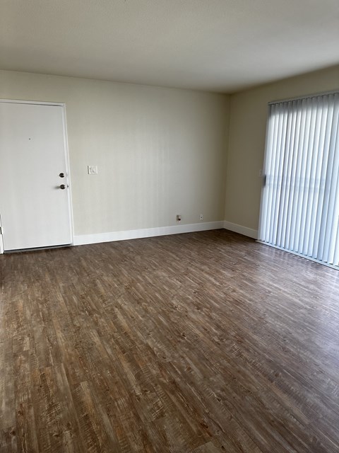 an empty living room with wood flooring and a closet