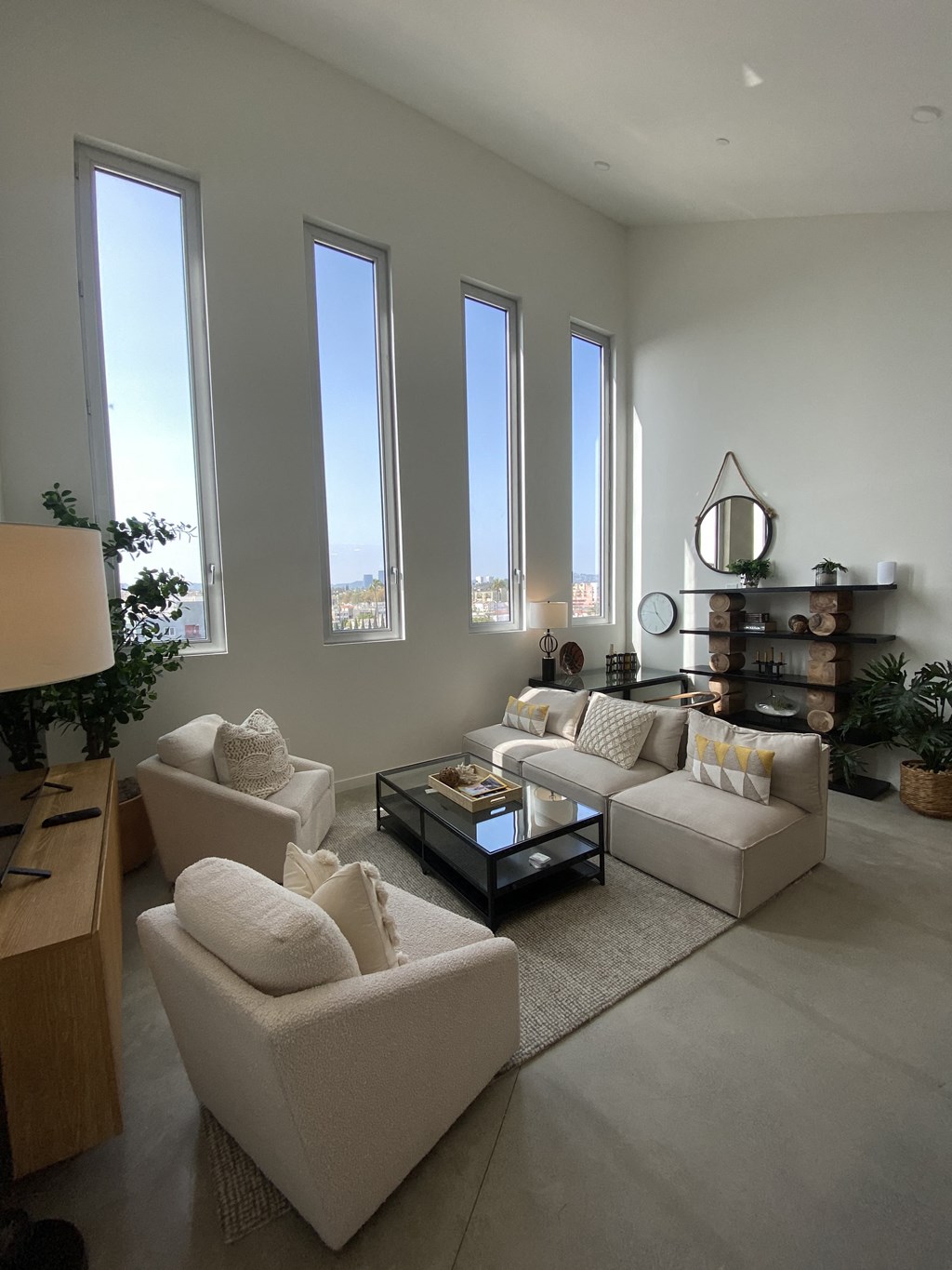 a living room with white furniture and tall windows