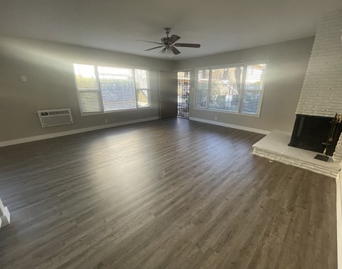 A spacious living room with a fireplace and a ceiling fan.