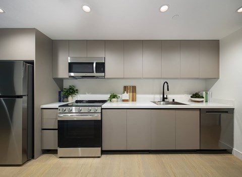 A modern kitchen with a stainless steel refrigerator, a microwave above the stove, and a sink with a faucet.