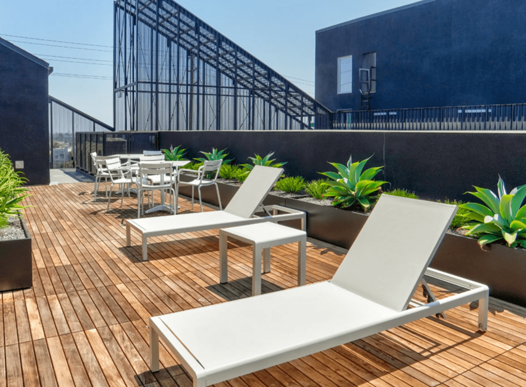 a rooftop deck with white lounge chairs and plants