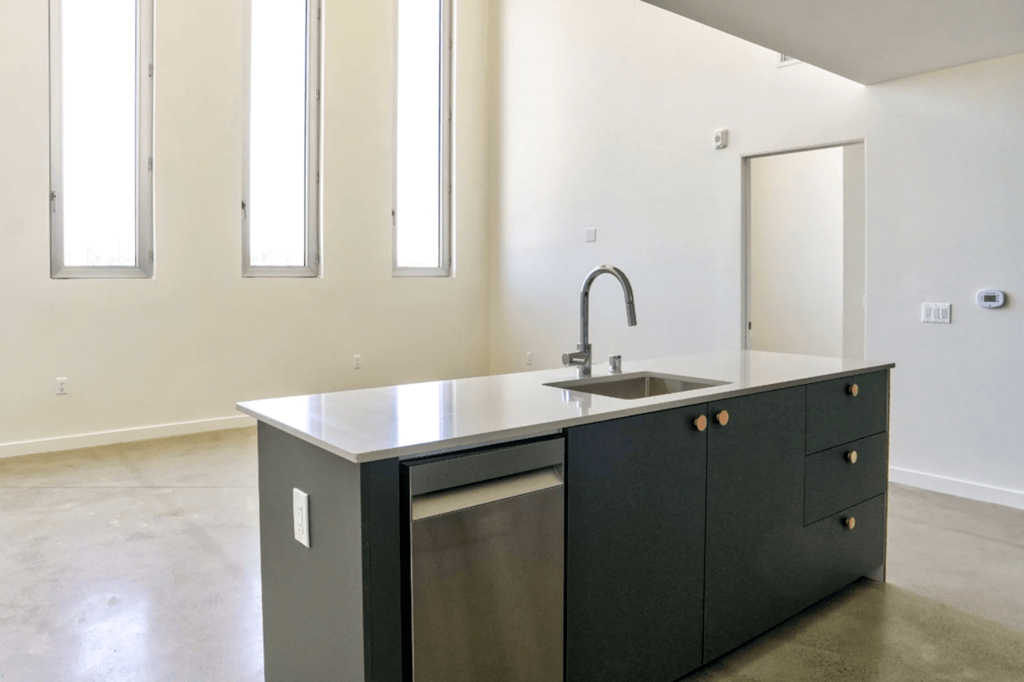 a kitchen with white walls and a black kitchen island with a stainless steel dishwasher