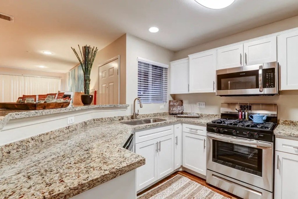 a kitchen with white cabinets and granite counter tops