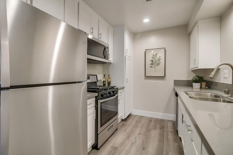 A modern kitchen with a stainless steel refrigerator and white cabinets.