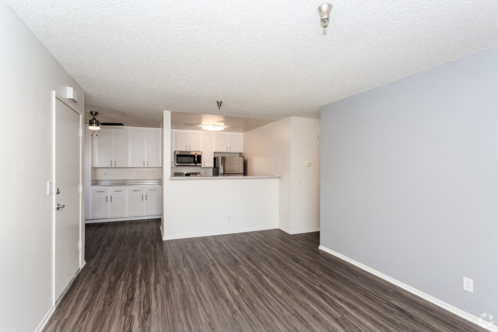 a spacious living room with a kitchen in the background