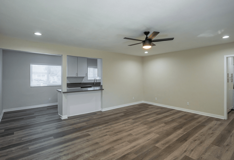 A room with a ceiling fan and wooden flooring.