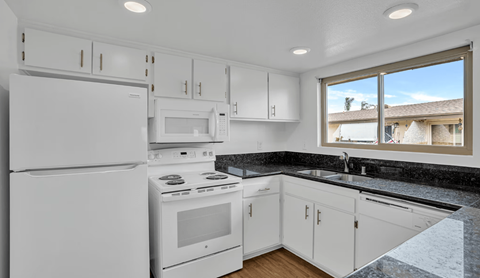A kitchen with white appliances and cabinets.