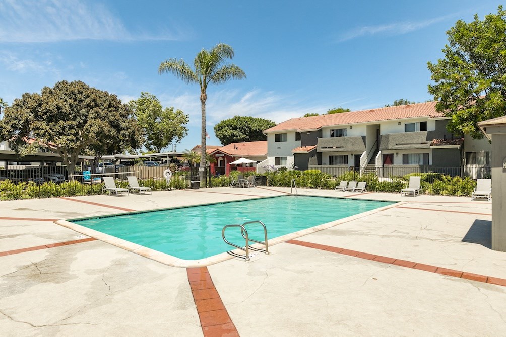 a swimming pool with chaise lounge chairs and palm trees in the background
