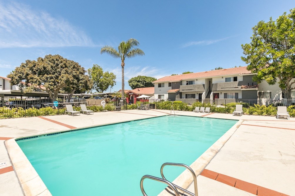 a swimming pool with chaise lounge chairs and palm trees in the background