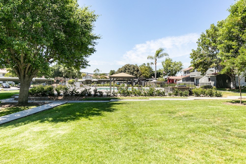 a grassy area with trees and buildings in the background