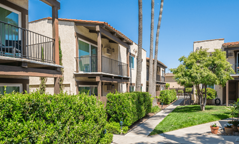 A row of apartment buildings with green bushes in front.