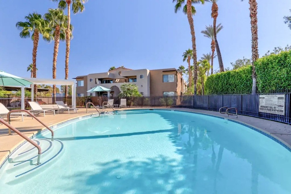 a swimming pool with palm trees and a building in the background