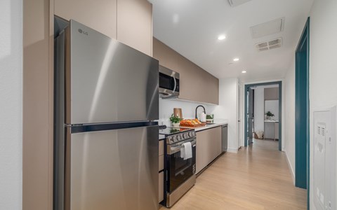 A modern kitchen with a stainless steel refrigerator and wooden flooring.