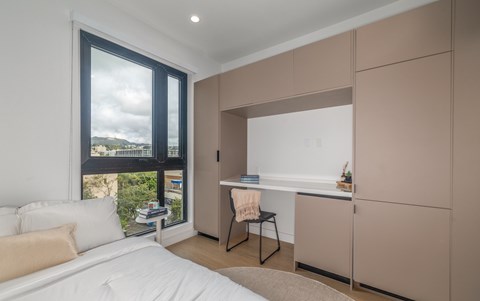 A bedroom with a large bed and a desk with a chair.