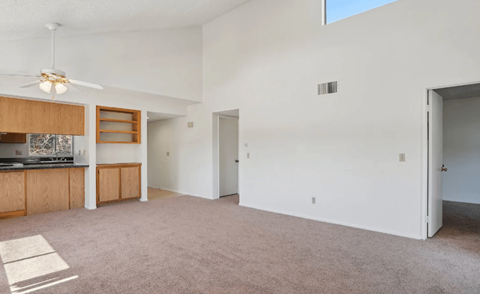 A spacious living room with a ceiling fan and a large window.