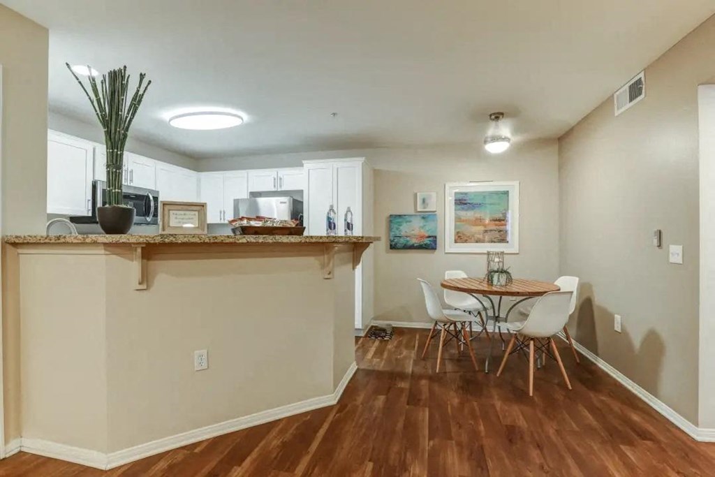 a dining room with a table and chairs in front of a kitchen with a bar