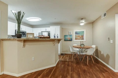 a dining room with a table and chairs in front of a kitchen with a bar