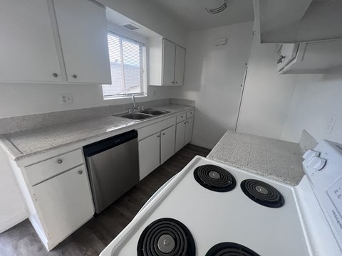 A white kitchen with a stove top oven and a dishwasher.