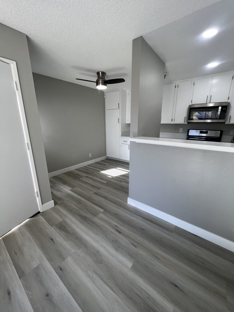 an open kitchen and living room with wood floors and white cabinets