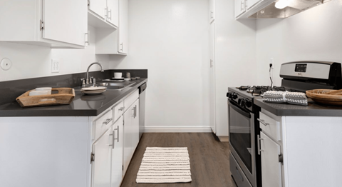 A kitchen with white cabinets and black countertops.