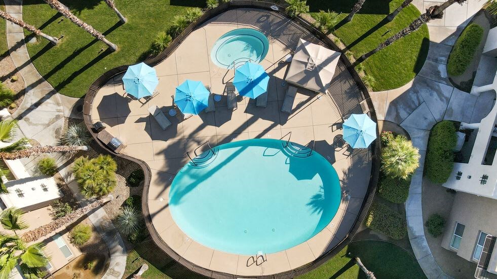 an aerial view of a swimming pool with tables and umbrellas