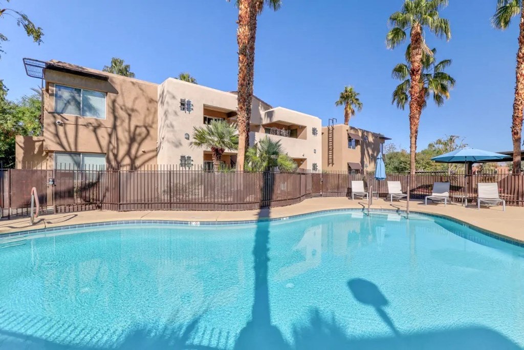 a swimming pool with palm trees and a building in the background