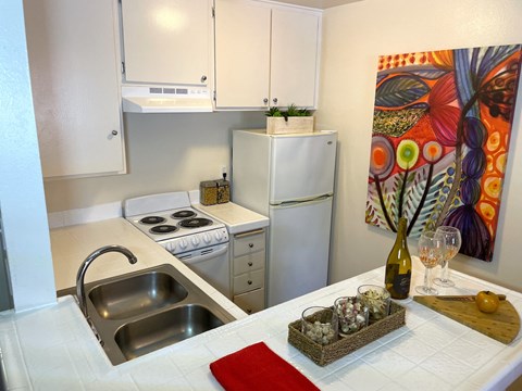 A kitchen with a white fridge, stove and a painting on the wall.