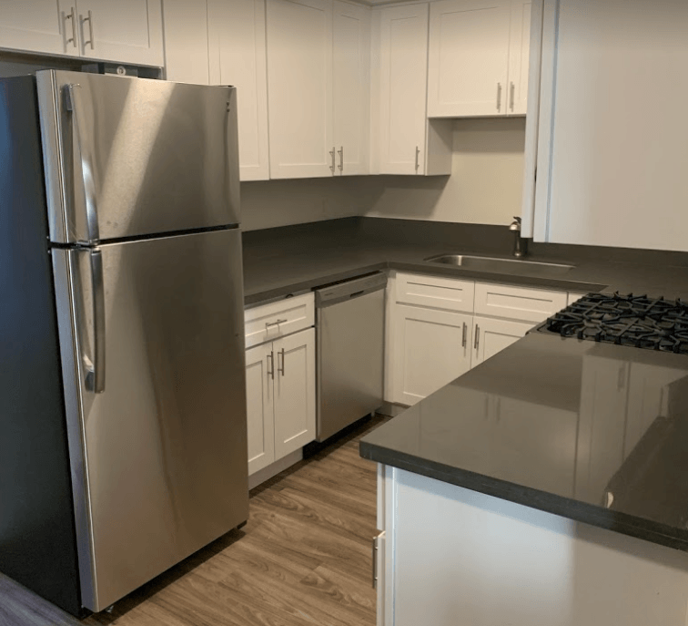 a kitchen with white cabinets and a stainless steel refrigerator