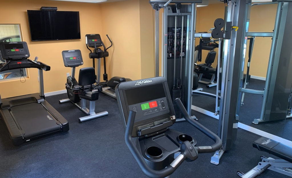 a gym with various exercise machines and a tv