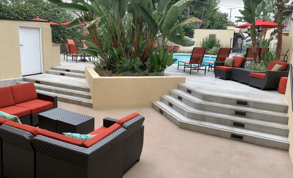 a patio with furniture and stairs around a pool
