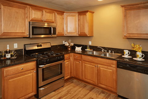 A kitchen with wooden cabinets and a black countertop.