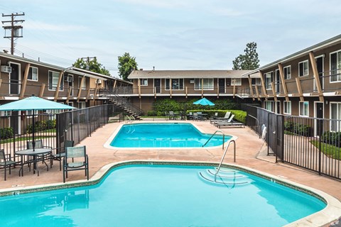 A swimming pool surrounded by a black fence and chairs.