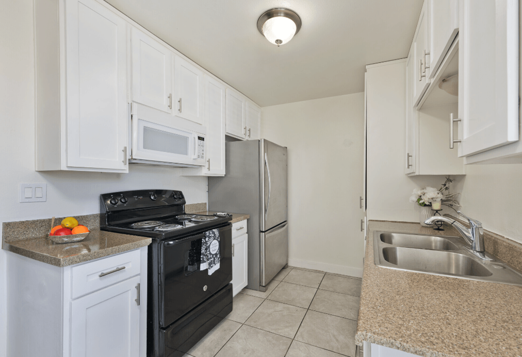 a kitchen with white cabinets and stainless steel appliances and a sink