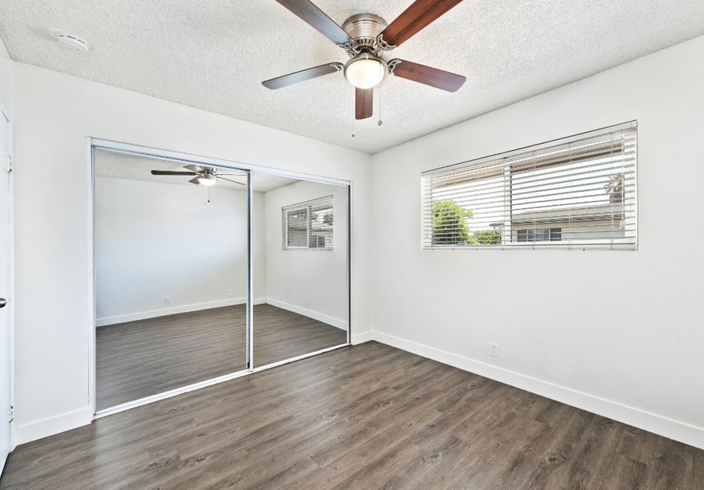 an empty living room with a ceiling fan and a window