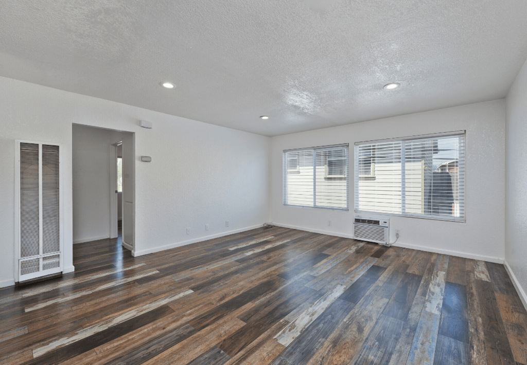 an empty living room with wood flooring and a window