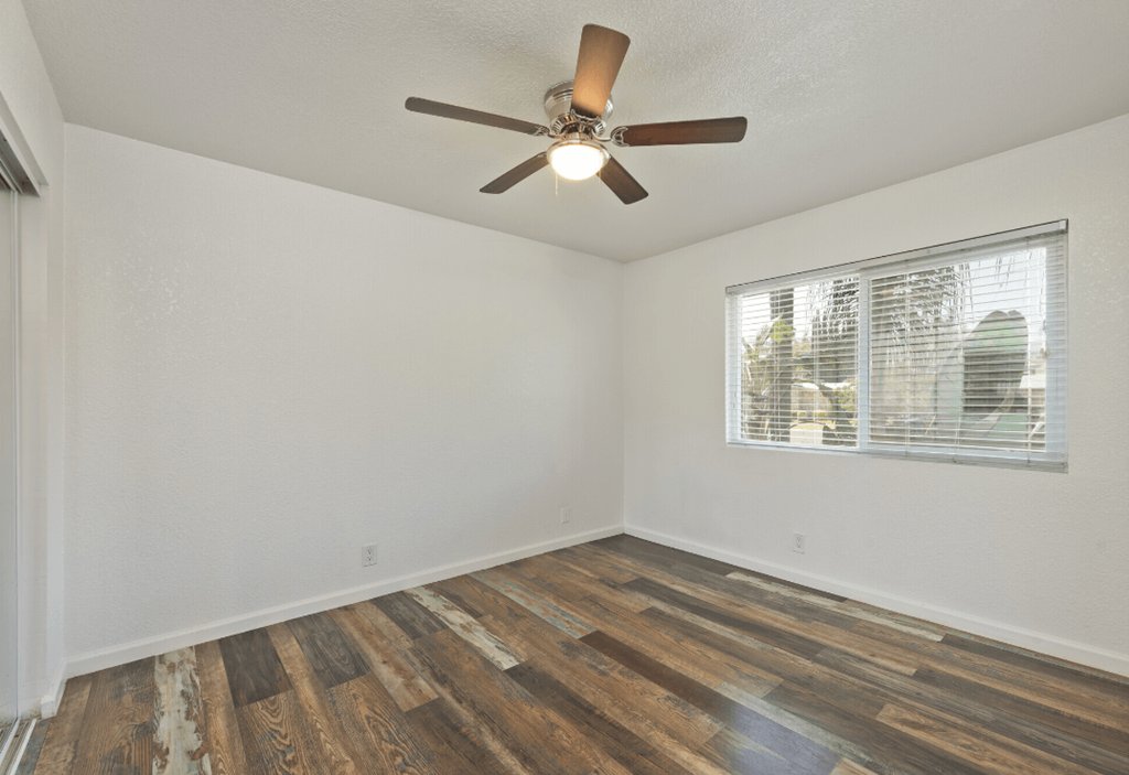 an empty living room with a ceiling fan and a window