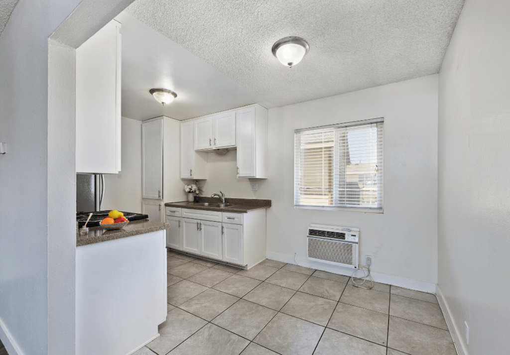 a kitchen with white cabinets and a sink and a window