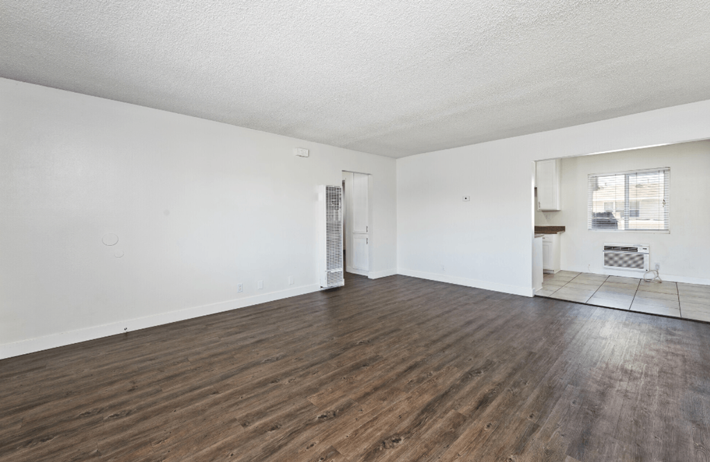 an empty living room with white walls and wood flooring