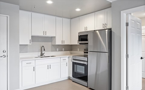 A modern kitchen with white cabinets and stainless steel appliances.