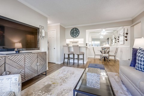A living room with a glass coffee table and a large TV.