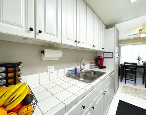 A kitchen with white cabinets and a black mat on the floor.